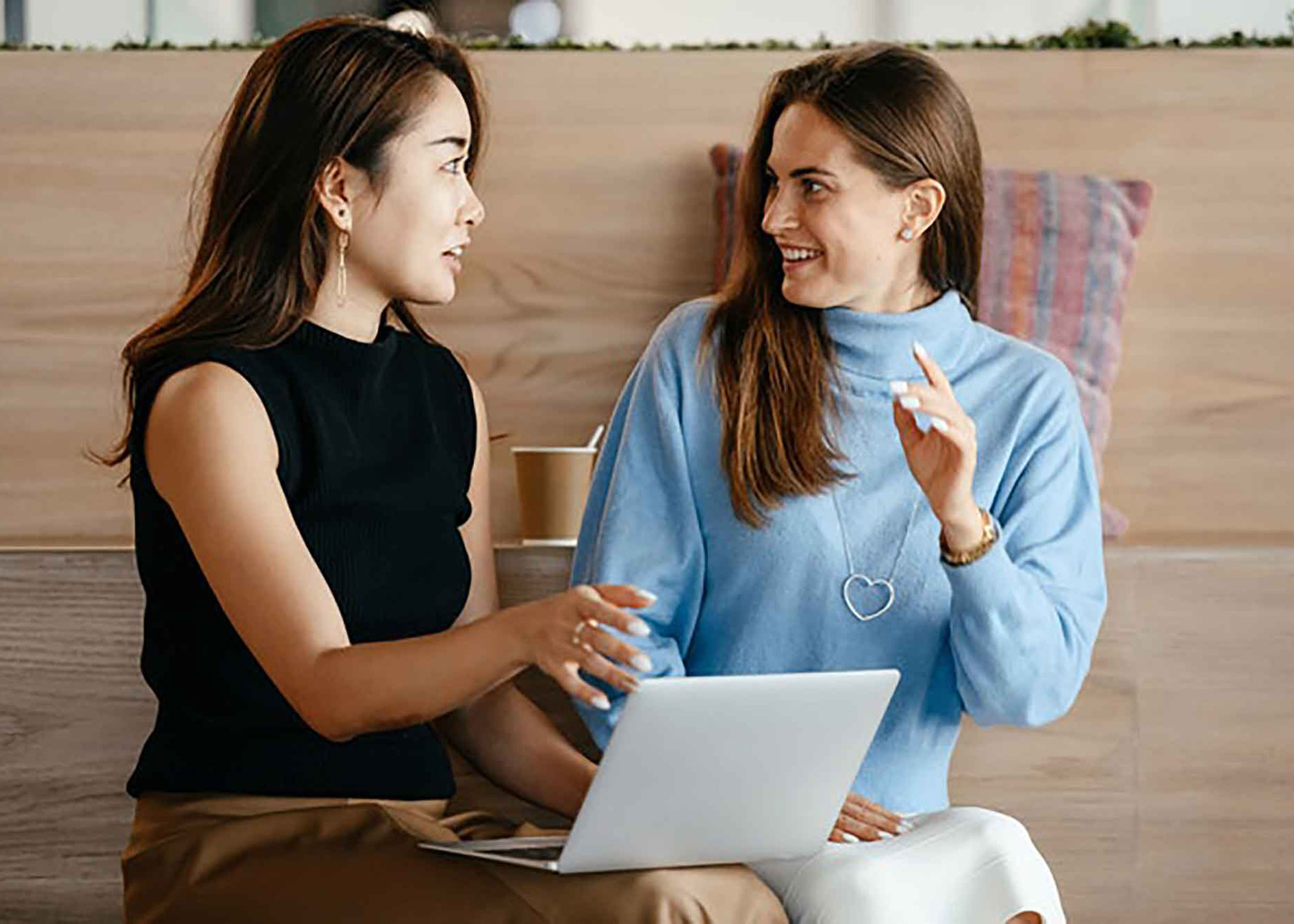 2 women talking aside with laptop